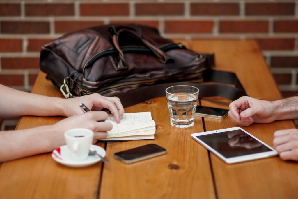 A group of people sitting at a table with coffee and cell phones.